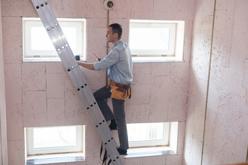 man standing on ladder changing a lightbulb.