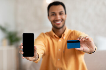 Excited man showing blank cellphone screen and credit card