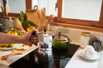 Man making morning coffee in moka pot on stove