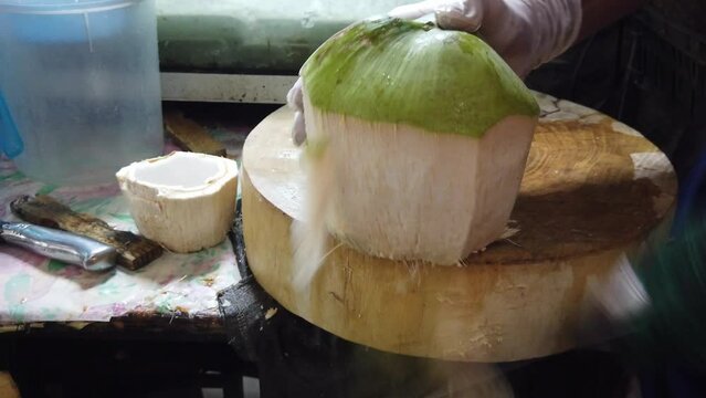 Man is peeling coconut with a knife.Green fresh coconut peeling and shelling with heavy chop knife for juice. 