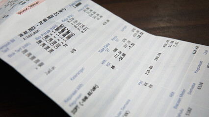 Obraz premium Close up view of utility electric bill receipt charge info on a wooden table.