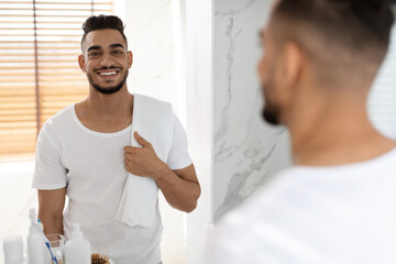 Self-Care Concept. Portrait Of Handsome Smiling Arab Man Posing In Bathroom Interior