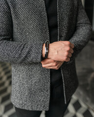 Obraz premium Businessman holds hands together. Man in a gray coat jacket. Stylish men's accessories up close.