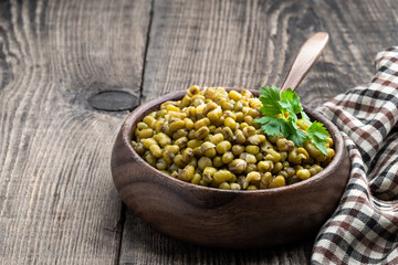 Boiled green mung beans in wooden bowl on rustic table
