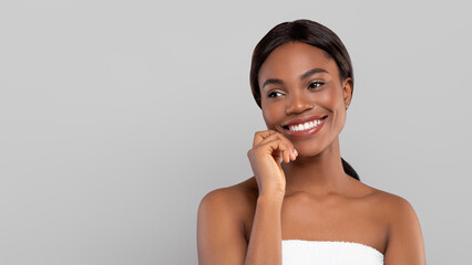 Smiling pretty young african american woman with shiny hair in towel looking at free space