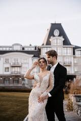 Beautiful bride with modern bouquet embracing with stylish groom in summer park. Sensual romantic moment. Wedding. Stylish and beautiful.