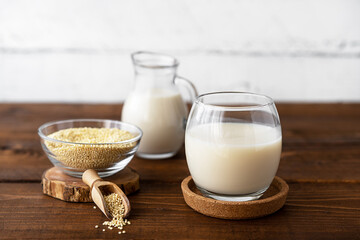 Millet milk in glass, jar and bowl on brown wooden table with withe wooden backside