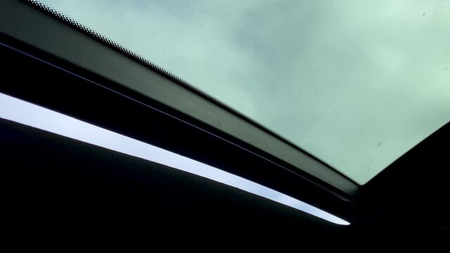 Car sunroof closing on a cloudy day - interior