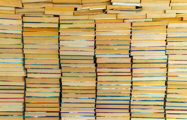 Endless wall of old books stack background. Colorful educational used books folded in many pile columns. Collecting in the library and how to choose only one book. horizontal