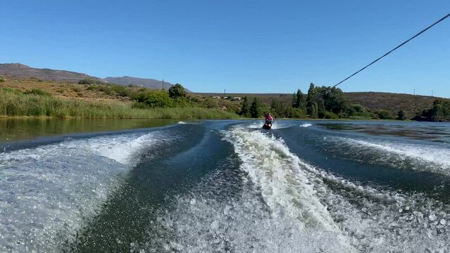 Woman on kneeboard behind speed boat on Bulshoek Dam, South Africa