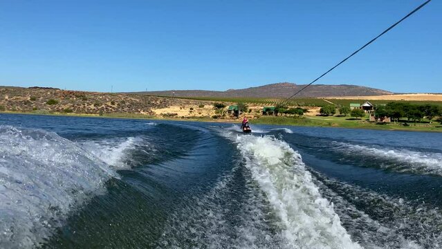 Woman on kneeboard behind speed boat on Bulshoek Dam, South Africa