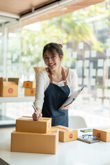 Portrait young attractive asia female owner startup look at camera work happy with box at home...