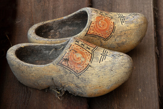 Pair of old dirty traditional Dutch wooden shoes on the wooden floor  