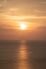 Sunset on the sea and through the clouds over. Tranquil seascape with the horizonal skyline.