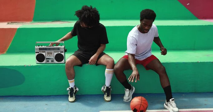 Young african people listening music from vintage boombox stereo outdoor after basketball match