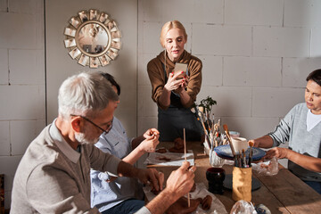 Teacher making photos at the smartphone of her senior students while holding master class