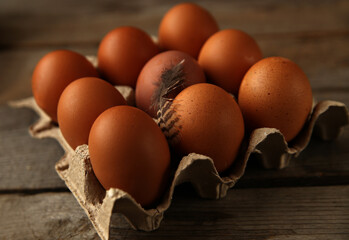 Brown chicken eggs in paper box on wooden surface