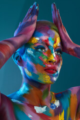 The colors we see and use are nothing less than magical. Studio shot of a young woman posing with multi-coloured paint on her face.