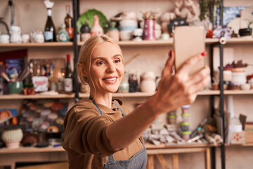 Overjoyed woman smiling while taking selfie at her smartphone