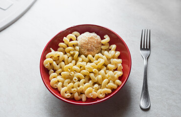 Tasty pasta with rissole in red bowl , fork on table  and top view. Pasta fusilli on white table. Traditional Italian cuisine healthy food. Simple fast carbs meal concept.	