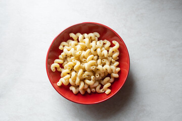 Tasty pasta in red bowl top view. Pasta fusilli on white table. Traditional Italian cuisine healthy food. Simple fast carbs meal concept.