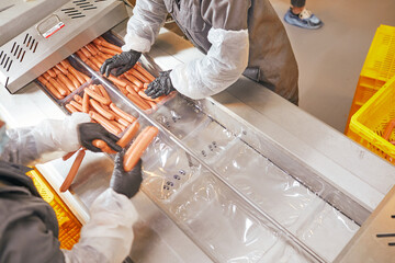 production of sausages from veal, chicken and pork meat, the worker holds sausages in his hands and...