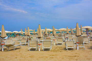 Beach with umbrellas and sun beds on coast in Pesaro, Italy