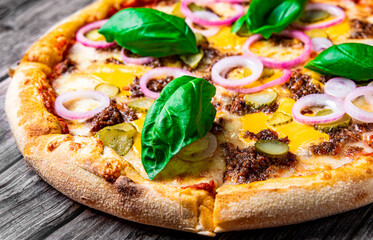 Pizza with cheese, Bolognese sauce and vegetables. Italian pizza on wooden background.