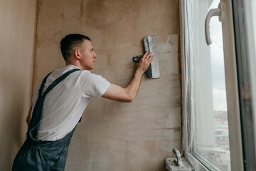 Worker applying putty mortar on the balcony wall