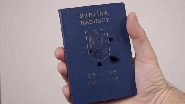 Ukrainian passport held by a man's hand. Holes in the document from gunshots. war in Ukraine. Russian aggression, occupiers