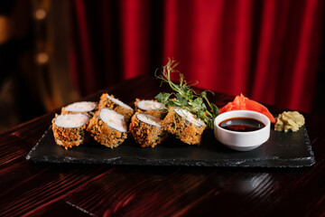Sushi roll set with ginger and wasabi on black stone with soy sauce.