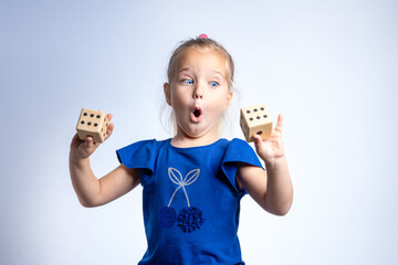 A girl with a surprised look holds playing dice in her hands. The concept of gambling, children's...
