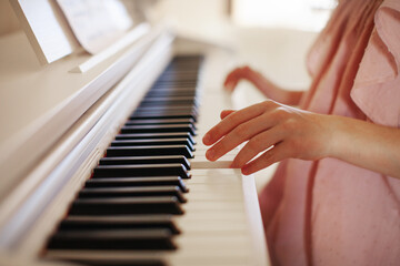 Close up girl hands playing piano keyboard. Blurred background © Anna Zhukkova