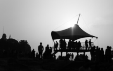 black and white silhouette of People watching sunset sunrise on a raised platform canopy atop a hill