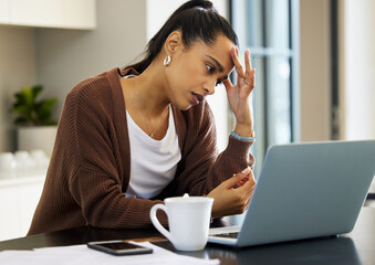 Working from home sure is a pain some days. Shot of a young woman looking stressed while working on...