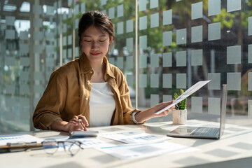 Close up accountant woman using calculator and laptop for do math finance on wooden desk in office and business working background, tax, accounting, statistics and analytic research concept