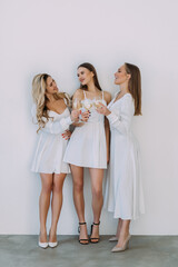 Young three women with glasses of wine celebrating on white beckground