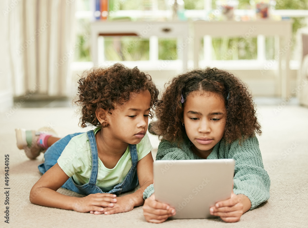 Sticker Theyre glued to the screen. Shot of two sisters using a digital tablet at home.