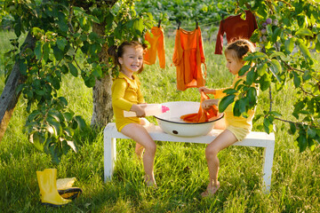 The girl pours liquid laundry detergent from a bottle. Sisters launder their clothes together in...