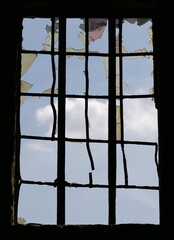 Carreaux d'une ancienne fenêtre cassés avec le ciel bleu et nuageux en arrière plan