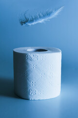 Toilet paper with blue steam over a feather, toilet paper on a blue background, soft like feather paper