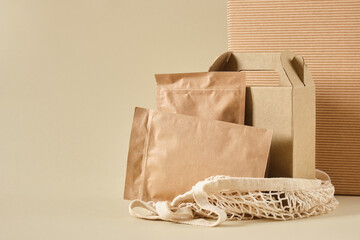 box and paper zip bags in a mesh bag for shopping, beige background top view, mock-up packaging for...