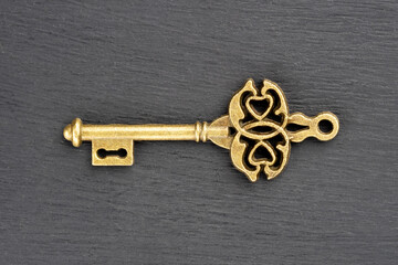 Bronze vintage antique key on black wooden background. Old keys concept