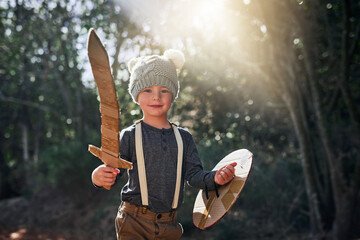 Ready for battle. Portrait of an adorable little boy playing with a cardboard sword and shield outside. © AS/peopleimages.com
