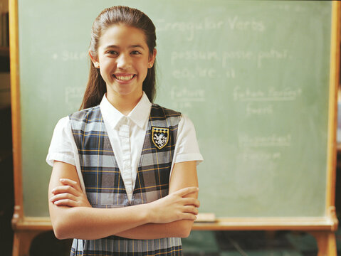 Portrait of girl (10-11) standing in front of chalkboard