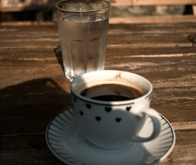 Cup of coffee and a glass of water on the wooden table.
