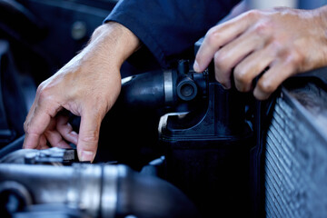 Hes hands on. Cropped shot of an unrecognizable male mechanic working on the engine of a car during a service.