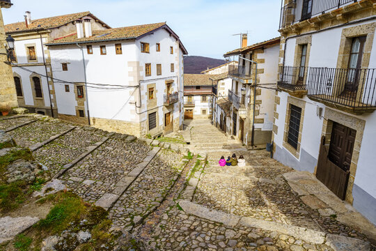 Old village houses with narrow cobbled streets and children playing, Candelario Salamanca.