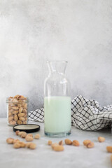 pistachio milk in a bottle and pistachios on a grey background.
