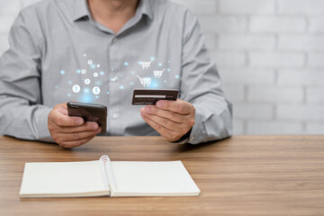 Close up a man holding a credit card and using a smartphone for payment online various expenses in the home office and notebook on table with virtual screen icon concept with texture and copy space